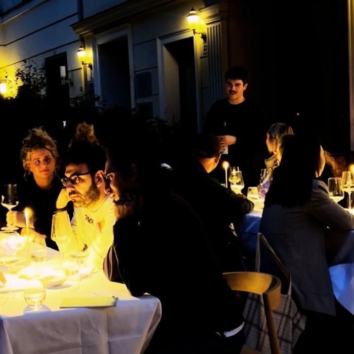 Geselliges Event im Freien mit Kerzenlicht und mehreren Gästen an gedeckten Tischen.