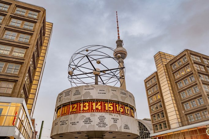 Fernsehturm und Weltzeituhr in Berlin, umgeben von modernen Bürogebäuden.