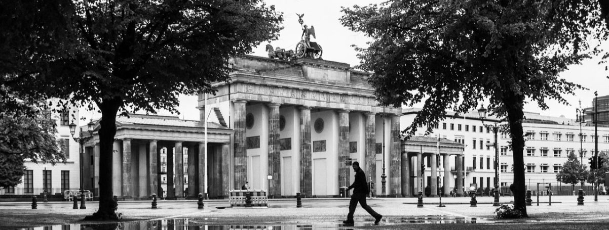 Das Brandenburger Tor mit Bäumen im Vordergrund, in Schwarzweiß.