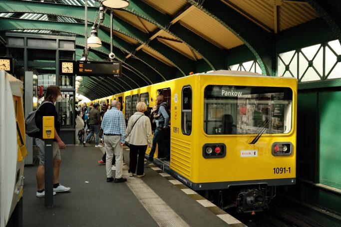 Menschen steigen an einer gelben U-Bahn-Station aus und ein.
